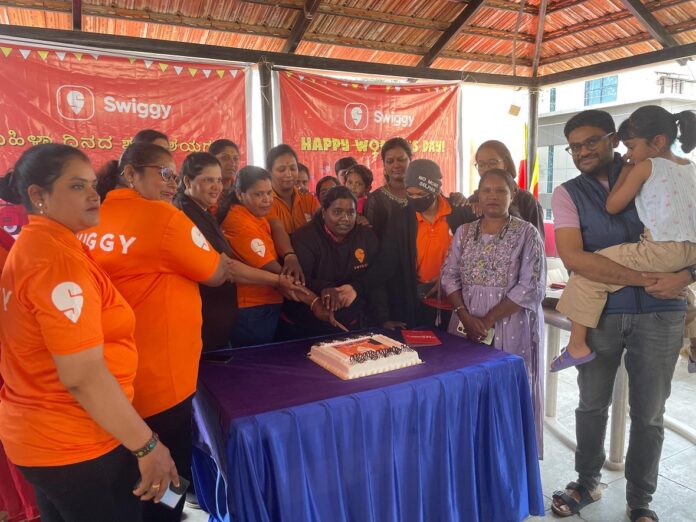 Swiggy female Delivery Executives cutting cake along on Women's Day